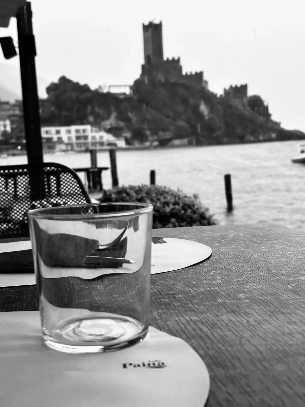 Bicchiere sul tavolo del Lido Paina con il Castello Scaligero sfocato sullo sfondo