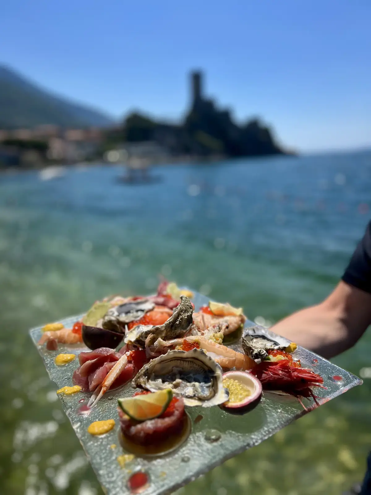 Crudo di mare con ostriche, scampi e gamberi servito davanti al castello di Malcesine