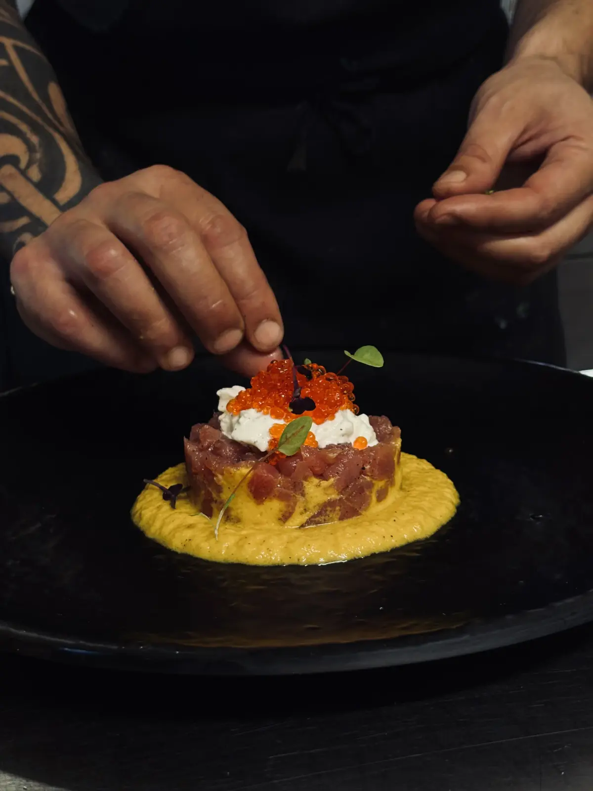 Lo chef rifinisce una tartare di tonno con uova di salmone