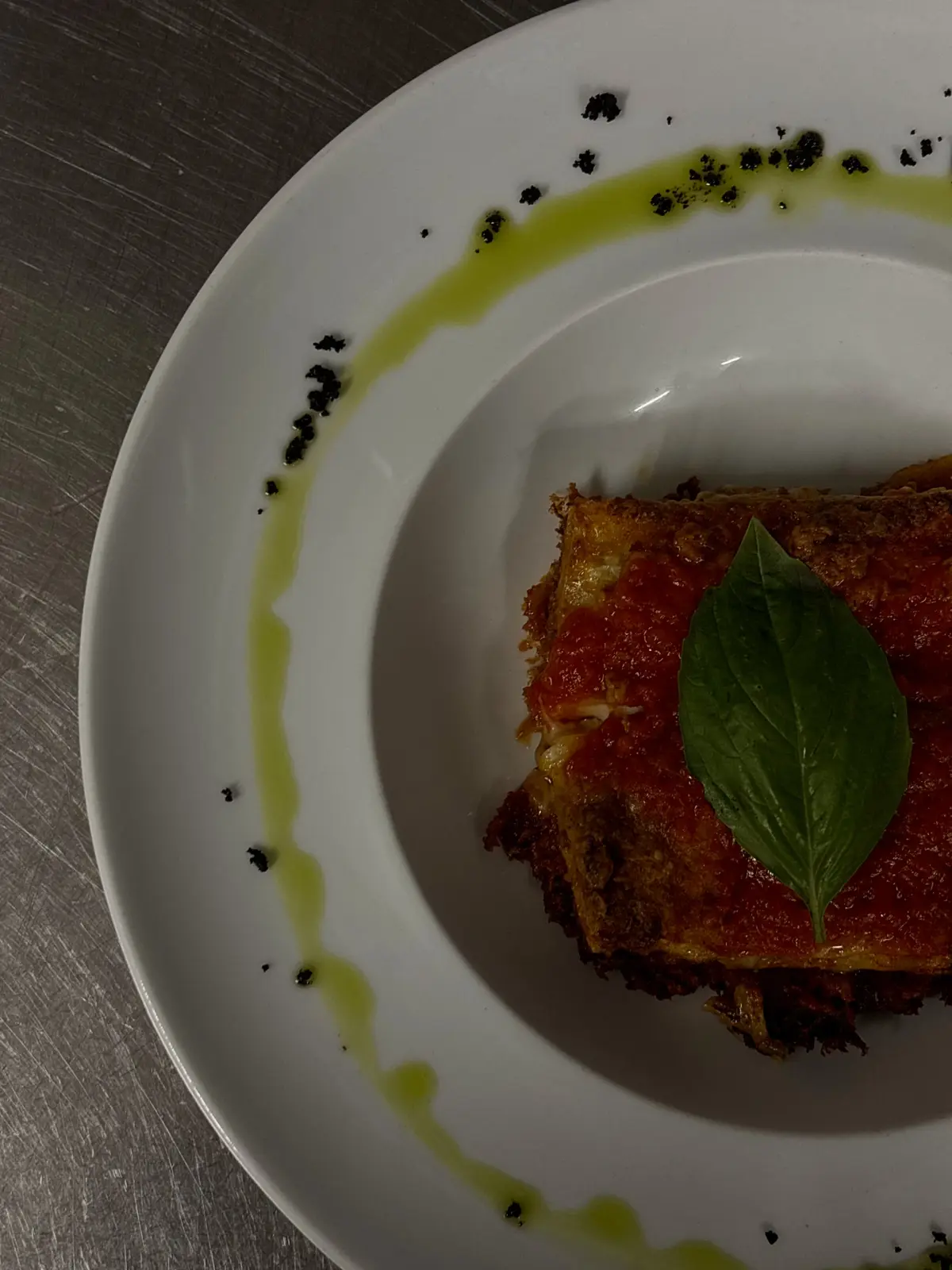 Porzione di parmigiana decorata con foglia di basilico