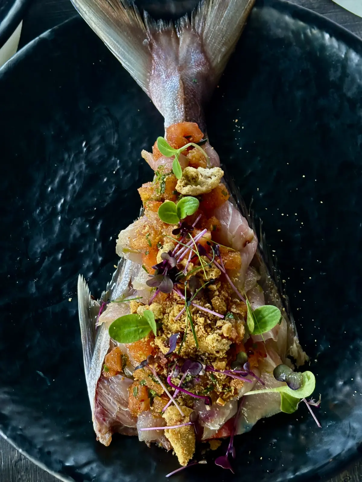 Crudo di pesce servito nel pesce intero con pomodorini e croccante