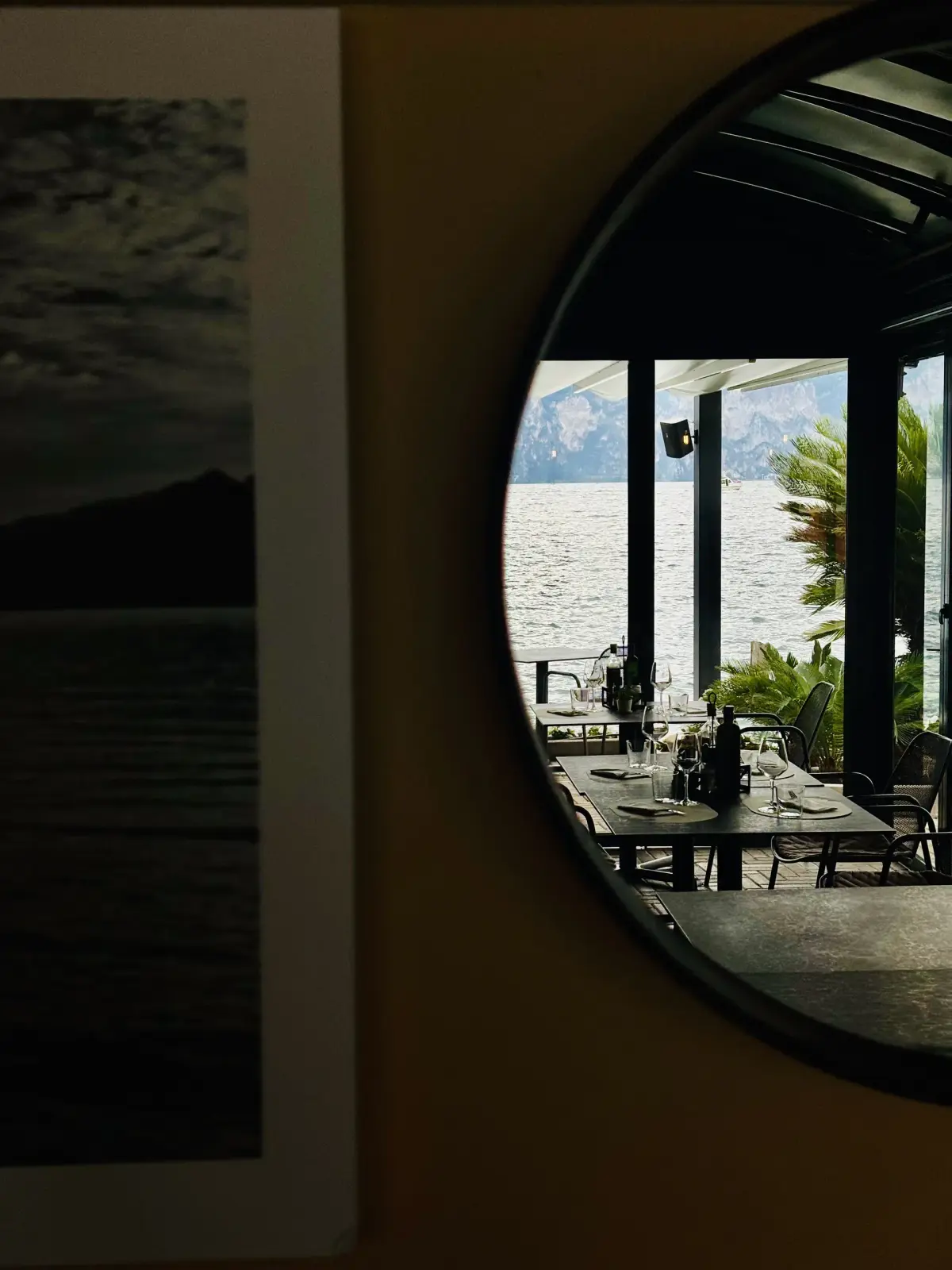 Specchio rotondo che riflette la sala e il Lago di Garda